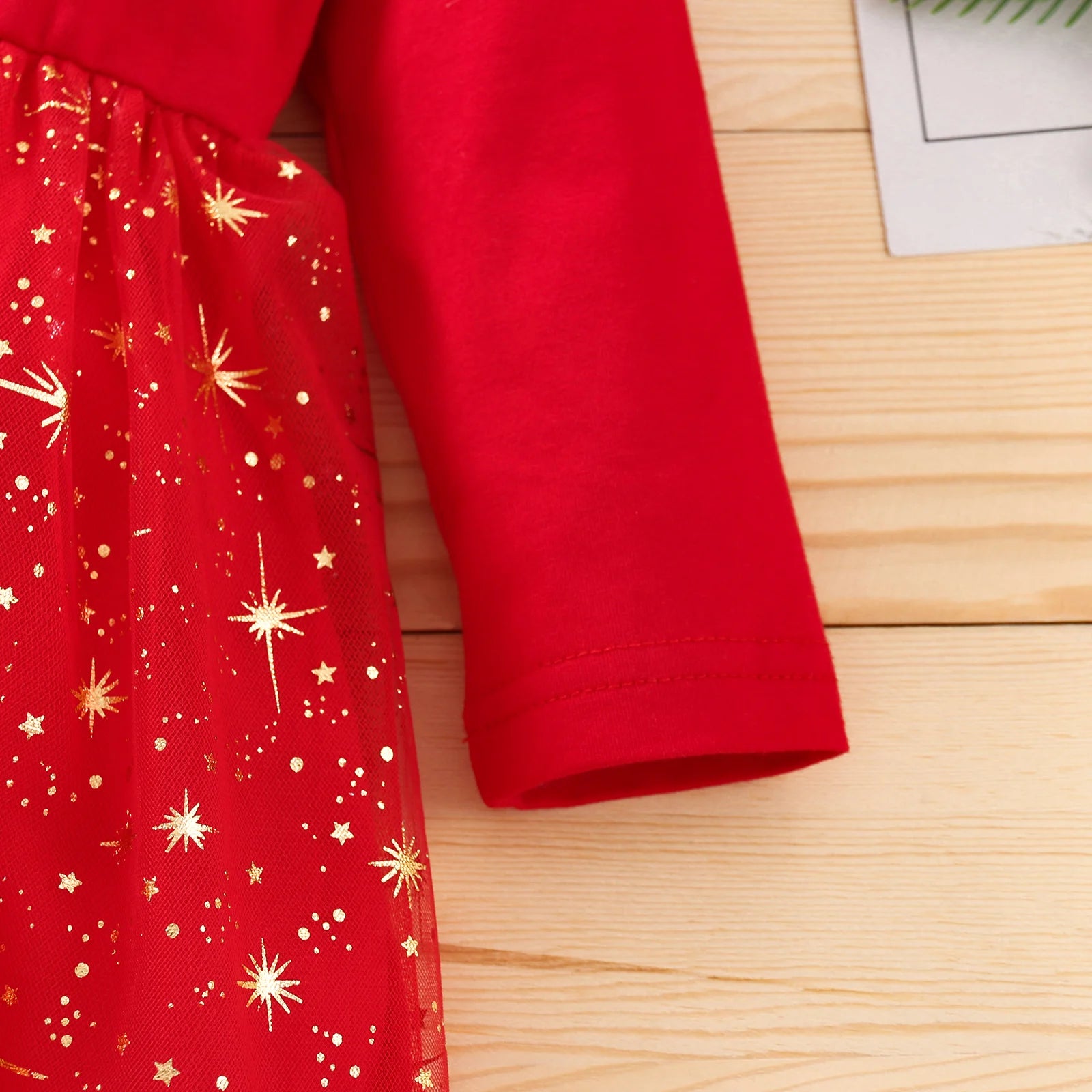 Red dress with gold star pattern on a wooden surface