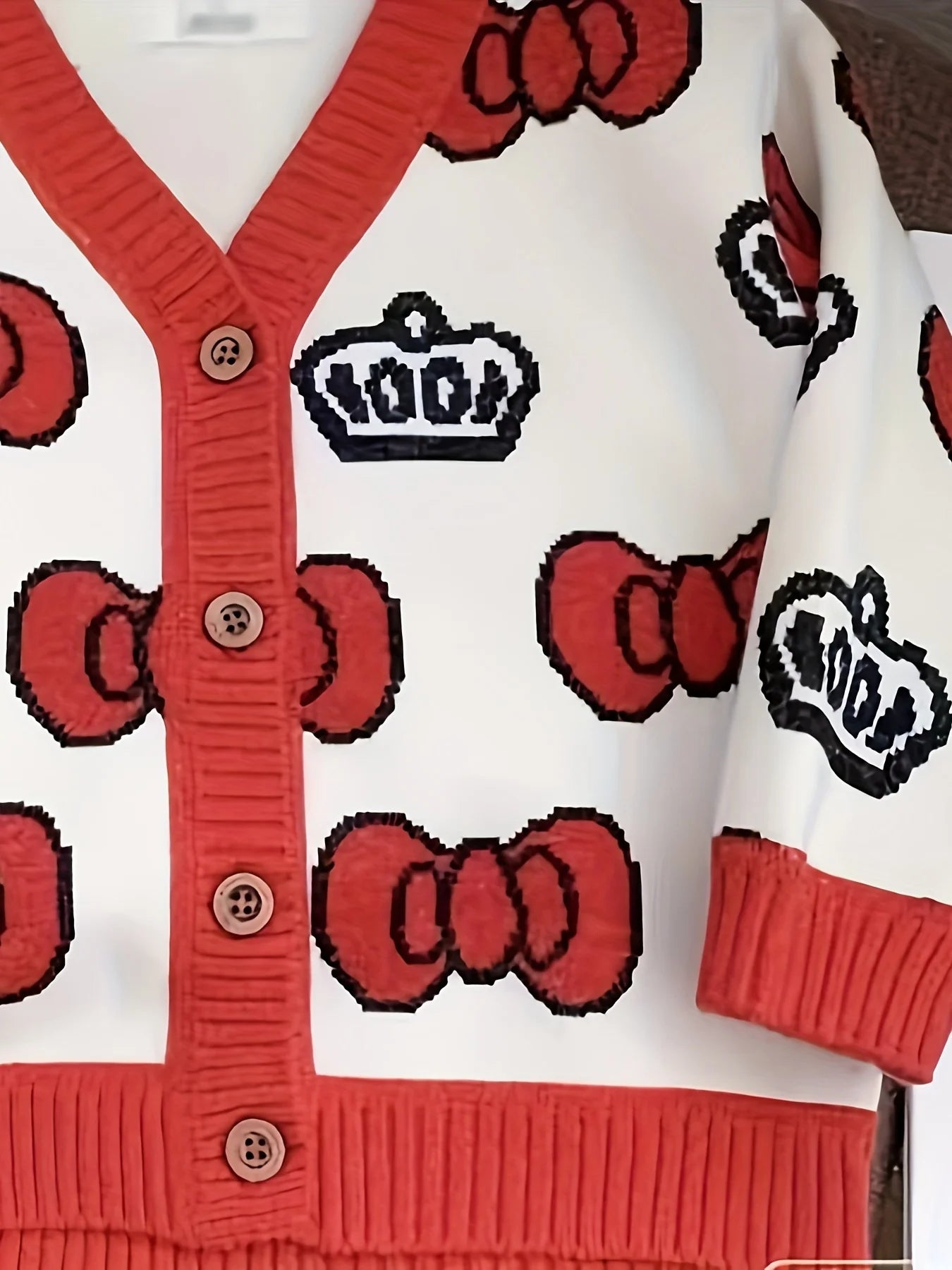 Cardigan with red bows and black crowns on a white background