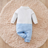 Baby onesie with white top and blue bottom on a fluffy pink rug