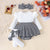 Baby outfit with white long-sleeve top, houndstooth pattern shorts, and headband on a textured surface.