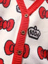 Close-up of a cardigan with red buttons and a pattern of red bows and crowns on a white background.