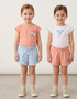 Two young girls wearing matching outfits with floral patterns on a plain background