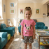 Young girl in a pink Minnie Mouse shirt standing in a colorful room with children's furniture and books