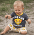 Child wearing a 'Lion King' shirt and shorts playing in the sand
