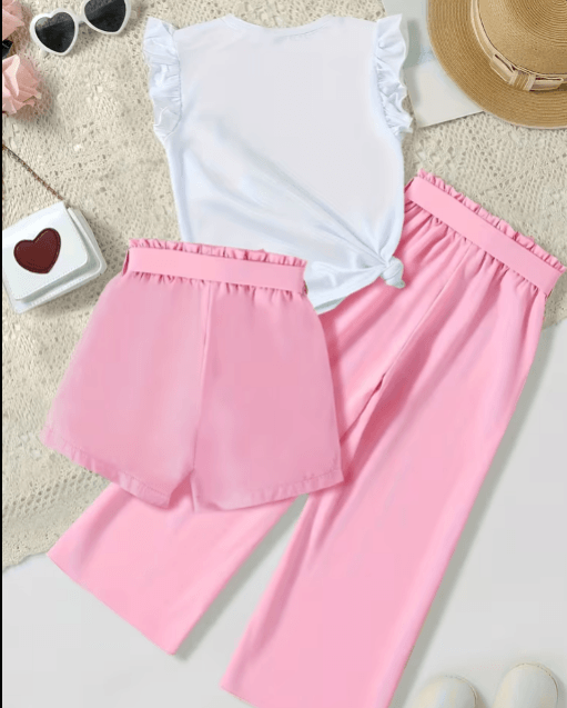 White top and pink pants on a textured surface with sunglasses and a hat in the background