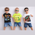 Three children wearing dinosaur-themed t-shirts and sunglasses against a white background