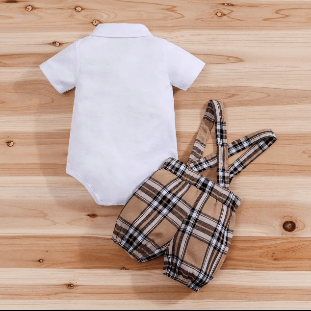 White baby onesie and plaid romper on a wooden surface