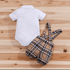 White baby onesie and plaid romper on a wooden surface