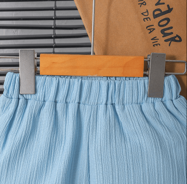 Blue pants on a hanger with a visible brand name on a cardboard background