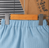 Blue pants on a hanger with a visible brand name on a cardboard background