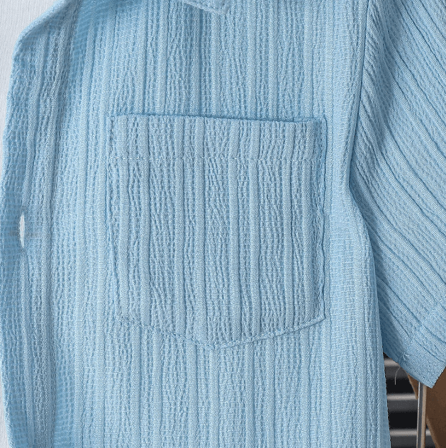 Close-up of a textured light blue shirt with a pocket