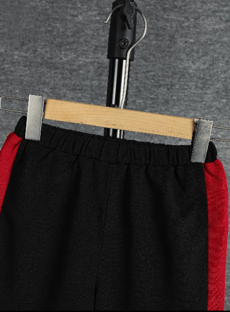 Black shorts with red accents on a hanger against a gray background