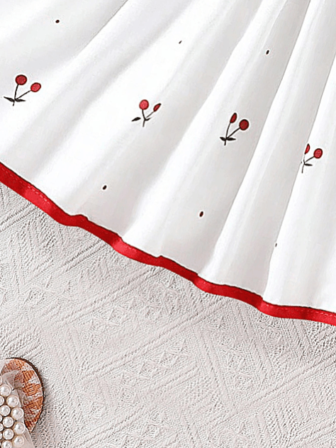 White fabric with red floral embroidery on a textured white surface
