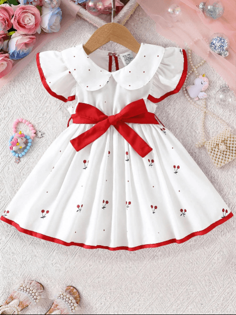 White dress with red trim and bow on a hanger, surrounded by decorative items.