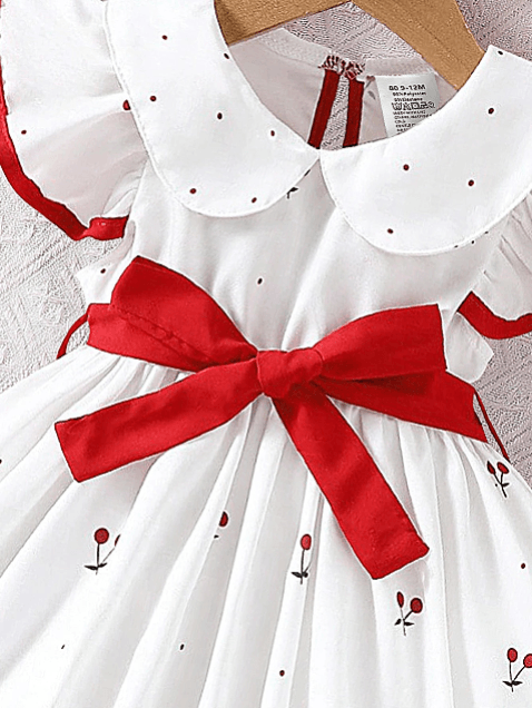 White dress with red bow and floral patterns on a hanger