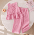 Pink striped children's outfit on a textured surface with a book and donut.