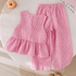Pink striped top and pants on a textured surface with a donut in the corner.