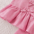 Close-up of a pink and white striped dress with a bow on a textured white background