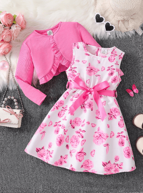 Pink floral dress with matching cardigan on a textured surface with decorative items.