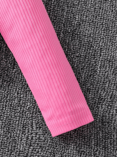 Close-up of a pink ribbed fabric sleeve on a textured gray surface