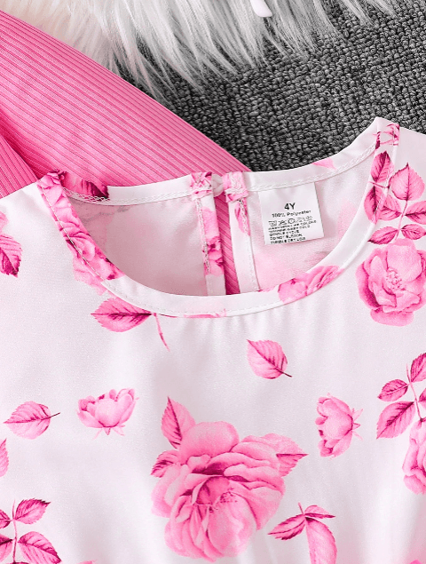 Close-up of a pink floral top with a brand label on a textured surface.