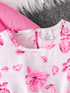 Close-up of a pink floral top with a brand label on a textured surface.
