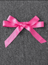 Pink ribbon bow on a gray textured background