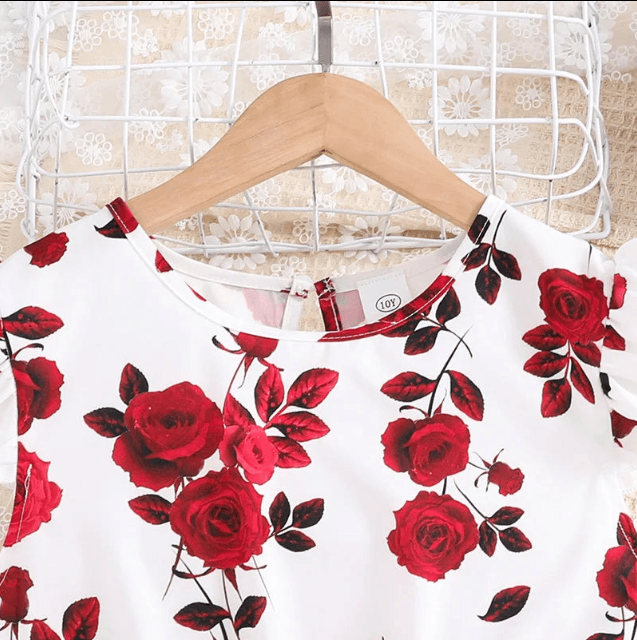 White shirt with red rose pattern on a hanger against a lace curtain background