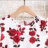 White shirt with red rose pattern on a hanger against a lace curtain background