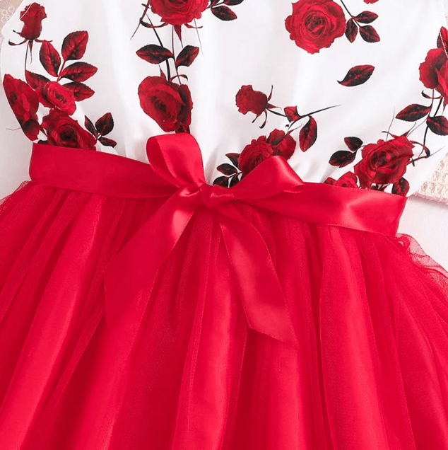 Red dress with floral lace overlay and a large bow on a white background