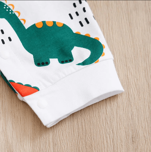Folded fabric with a green dinosaur design on a wooden surface