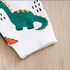 Folded fabric with a green dinosaur design on a wooden surface