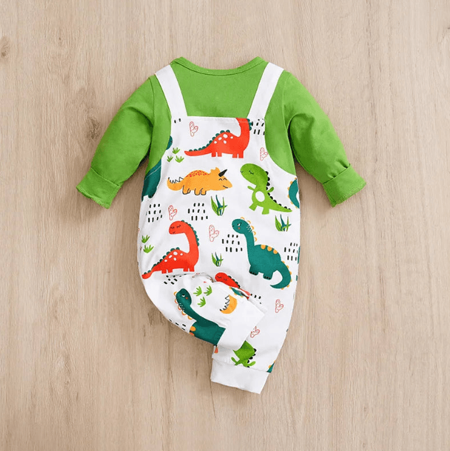 Baby outfit with green long-sleeve shirt and dinosaur-patterned overalls on a wooden surface