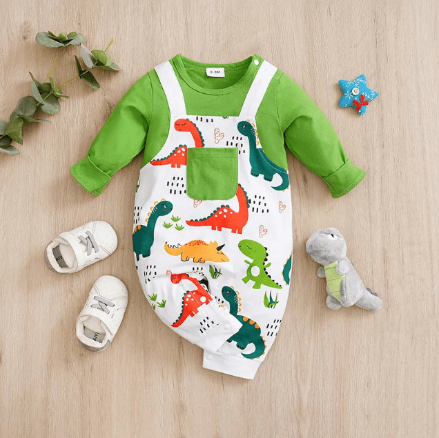 Baby outfit with green long-sleeve top and dinosaur-patterned overalls on a wooden surface.