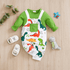 Baby outfit with green long-sleeve top and dinosaur-patterned overalls on a wooden surface.