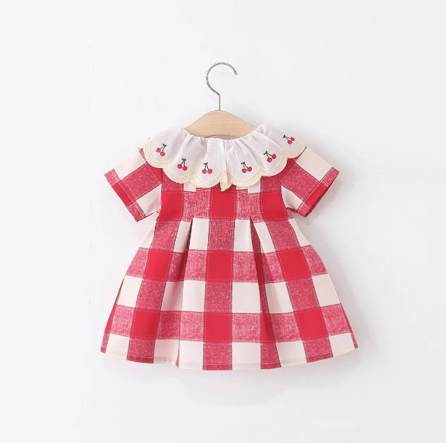 Red and white checkered dress with cherry collar on a hanger against a white background