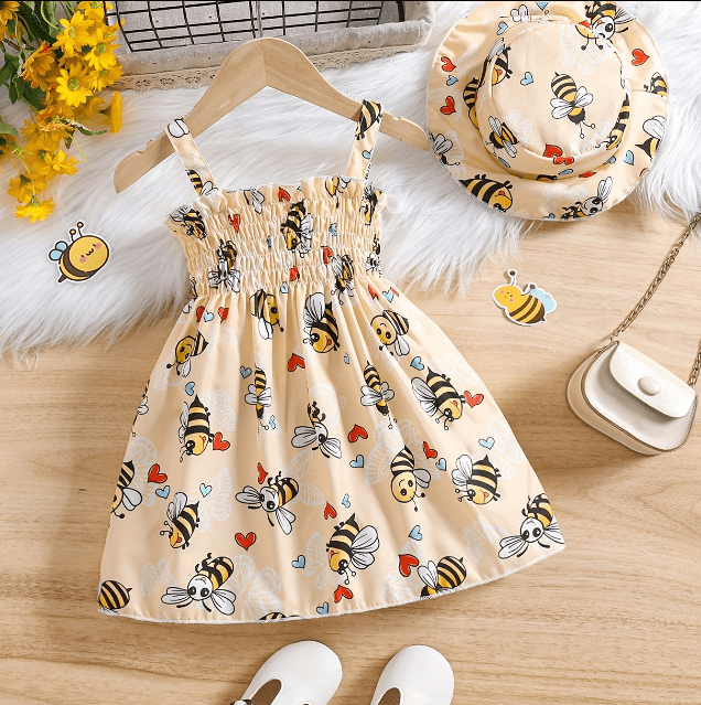 Beige dress with bee pattern on a wooden surface, accompanied by a matching hat and white shoes.