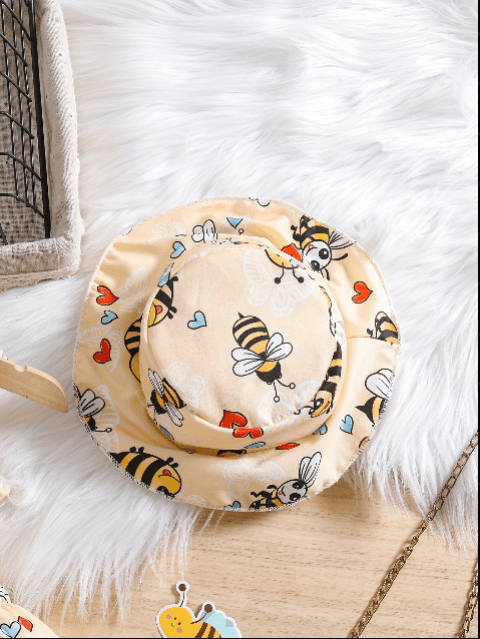 Beige bucket hat with bee pattern on a white fluffy surface