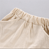 Close-up of beige, linen-textured shorts featuring an elastic waistband, side pockets, and a central vertical seam.