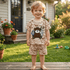 Child wearing a patterned outfit with a bear design in a backyard setting