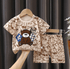 Children's clothing set with teddy bear design on a hanger against a dark curtain background.