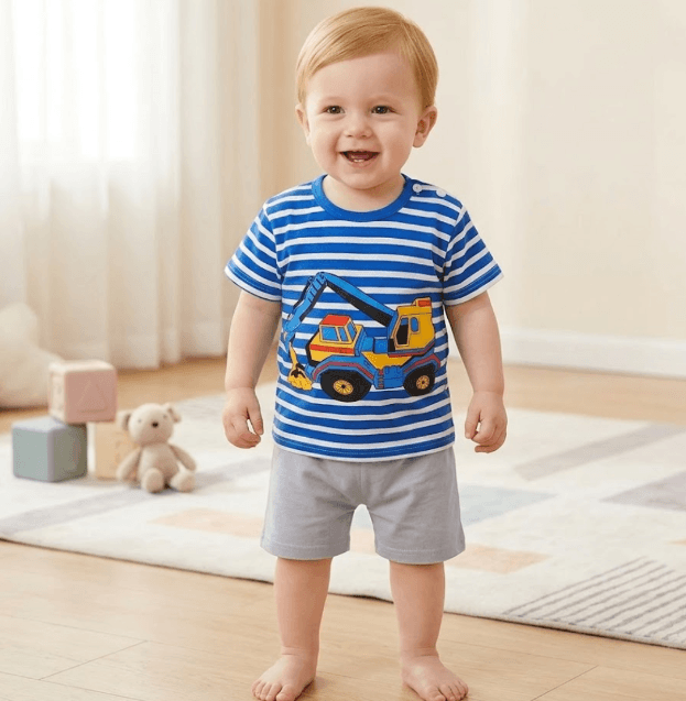 Child wearing a blue and white striped shirt with a truck design, standing on a wooden floor.