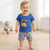 Child wearing a blue shirt with dinosaur designs in a room with toys and blocks.