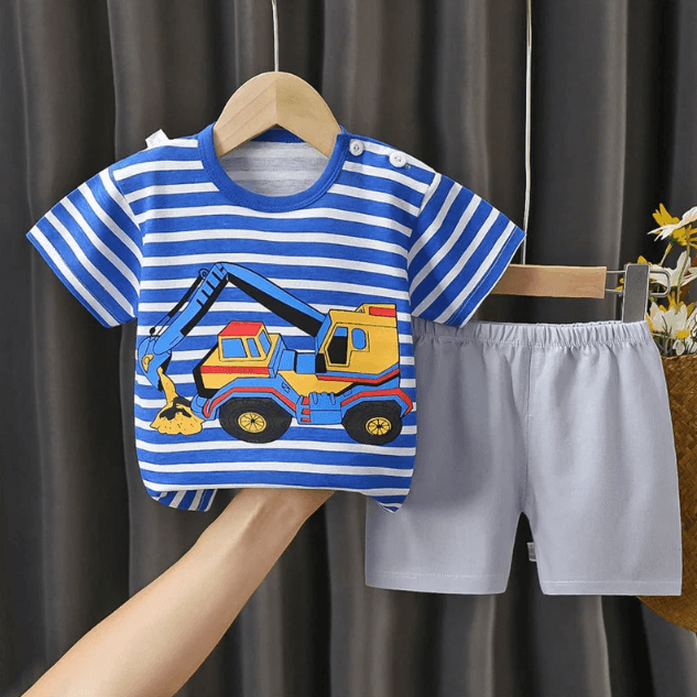 Children's blue and white striped shirt with a construction vehicle design and white shorts on a hanger against a dark curtain background.