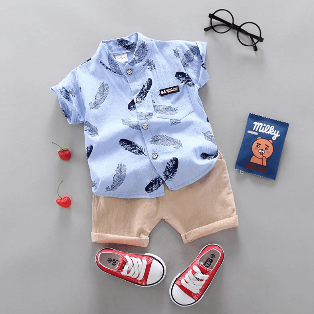 Children's outfit with blue shirt, beige shorts, red sneakers, and glasses on a gray background.