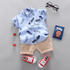 Children's outfit with blue shirt, beige shorts, red sneakers, and glasses on a gray background.