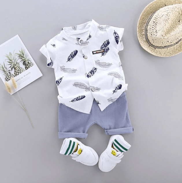 Baby outfit with white shirt and shorts, socks, and hat on a gray background