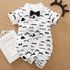 Baby romper with mustache and bow tie pattern on a textured surface