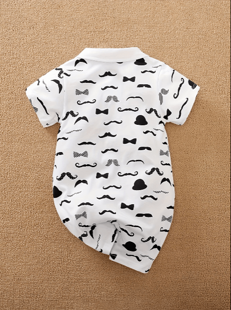 White baby onesie with black mustache and bow tie patterns on a beige background