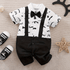 Baby outfit with white shirt, black suspenders, and bow tie on a beige surface.